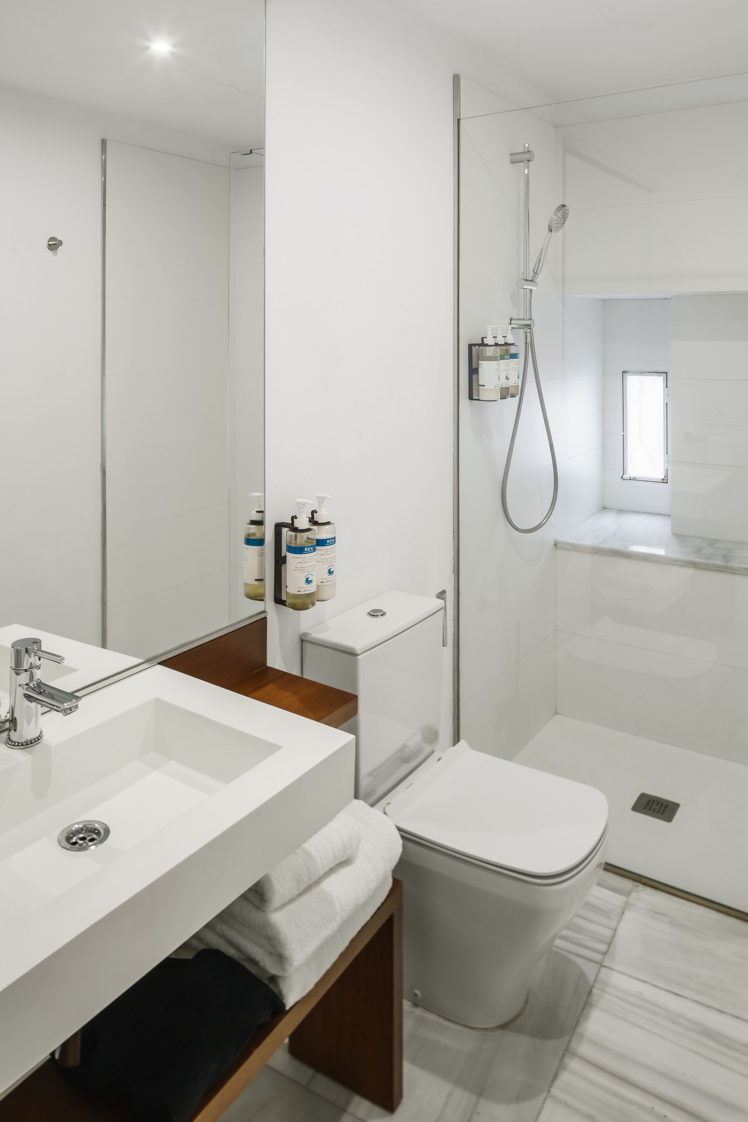 Egy modern fürőszoba fehér mosdókagylóval, tükörrel és WC-vel.
