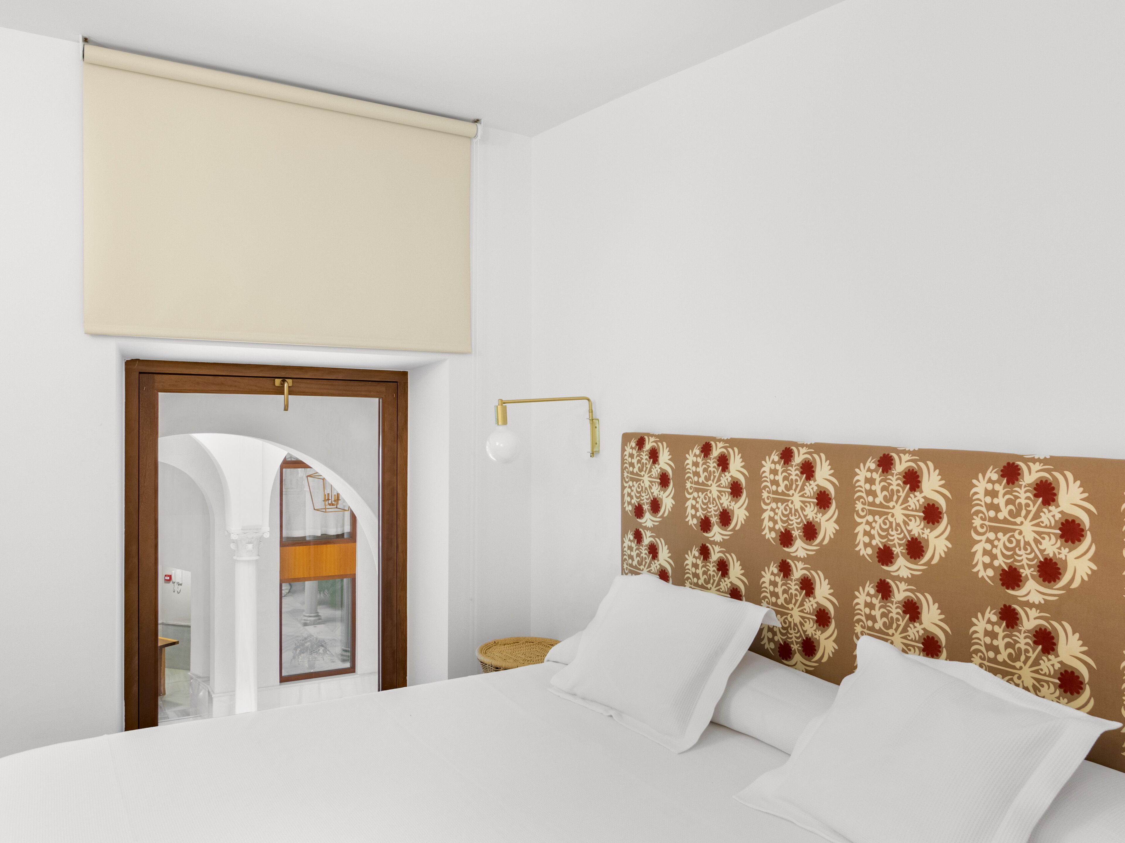 Une chambre d’hôtel comprenant un lit, une table de chevet, une lampe et une porte donnant accès à une salle de bain.