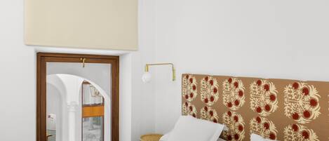 Une chambre d’hôtel comprenant un lit, une table de chevet, une lampe et une porte donnant accès à une salle de bain.