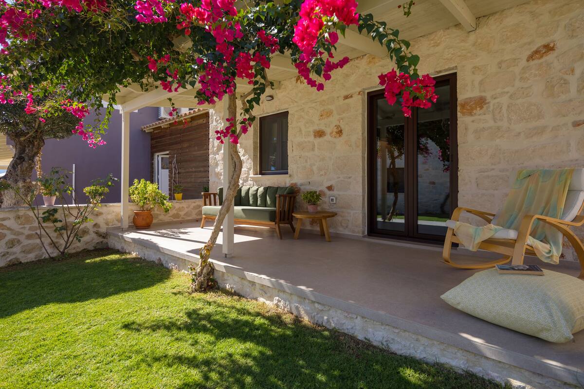 A stone building with a covered porch, a small garden, and outdoor seating.