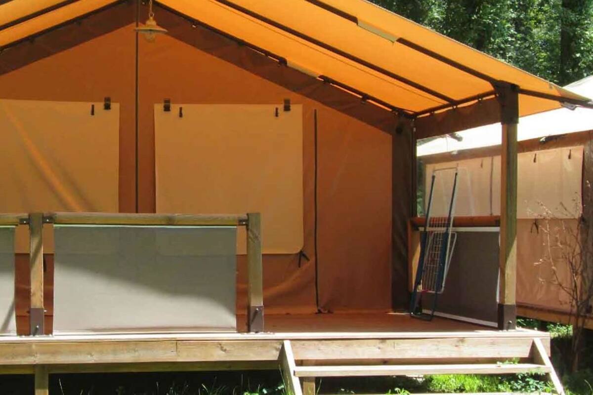 Una estructura tipo tienda con una plataforma elevada y un techo sostenido por vigas de madera.