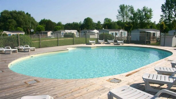 A swimming pool with lounge chairs and a wooden deck.