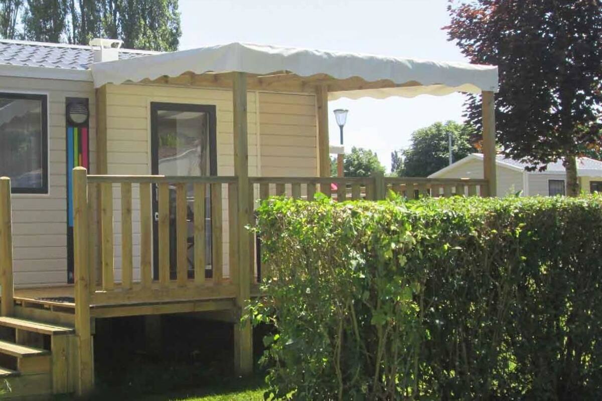 Una casa móvil con terraza de madera y porche cubierto.