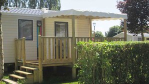 A mobile home with a wooden deck and a covered porch.