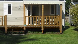 A mobile home with a wooden deck and a small porch.