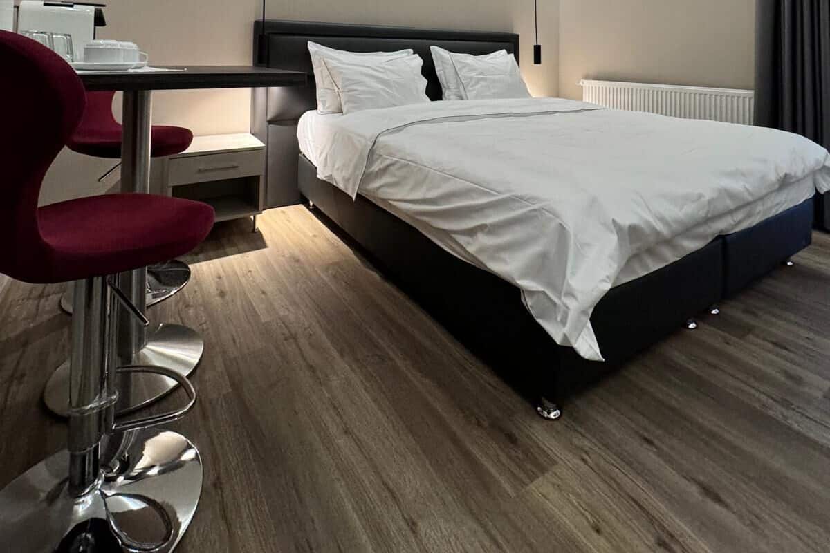A modern hotel room with a bed, a desk with a chair, and a radiator.