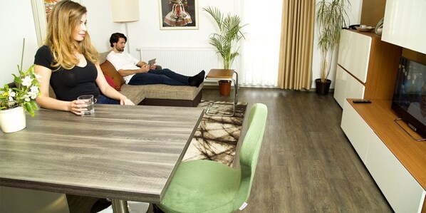 Uma sala de estar moderna com sofá, mesa de jantar e televisão.