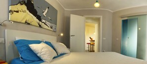 A bedroom with a bed, a painting, a door, and a small table with a pineapple. - B&B Anacleto (Luogosanto)