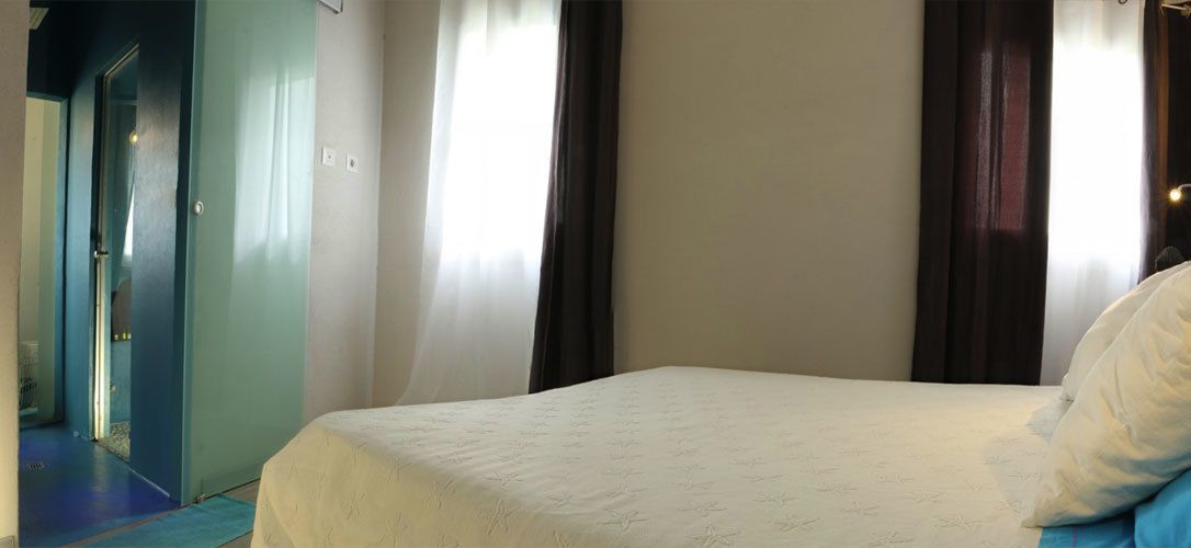 A hotel room with a bed, a door, and curtains.