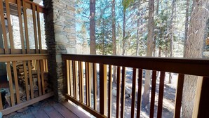 Une terrasse en bois avec un mur en pierre et une vue sur une forêt.