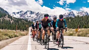 A group of cyclists on a paved road with a mountainous backdrop.