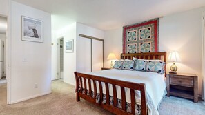 A bedroom with a wooden bed, two bedside tables with lamps, a quilted headboard, and a door leading to another room. - Summit #273 2 Bedroom Condo by RedAwning (Mammoth Lakes)
