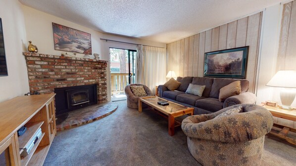 A cozy living room with a brick fireplace, a sofa set, a coffee table, and a patterned armchair. - Summit #273 2 Bedroom Condo by RedAwning (Mammoth Lakes)