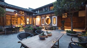 A courtyard with a wooden table, chairs, and potted plants.
