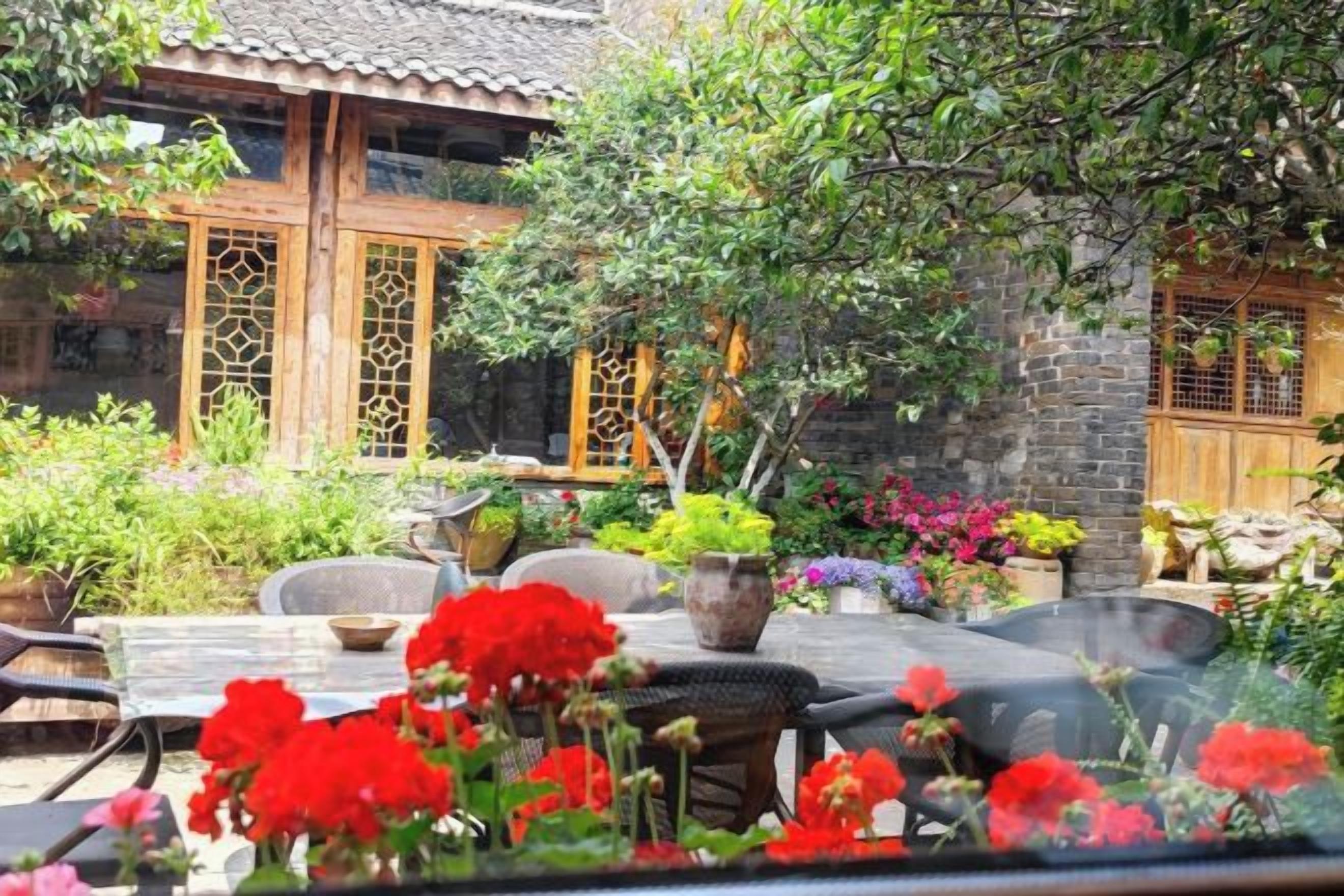 A traditional courtyard with a dining table, chairs, and potted plants.
