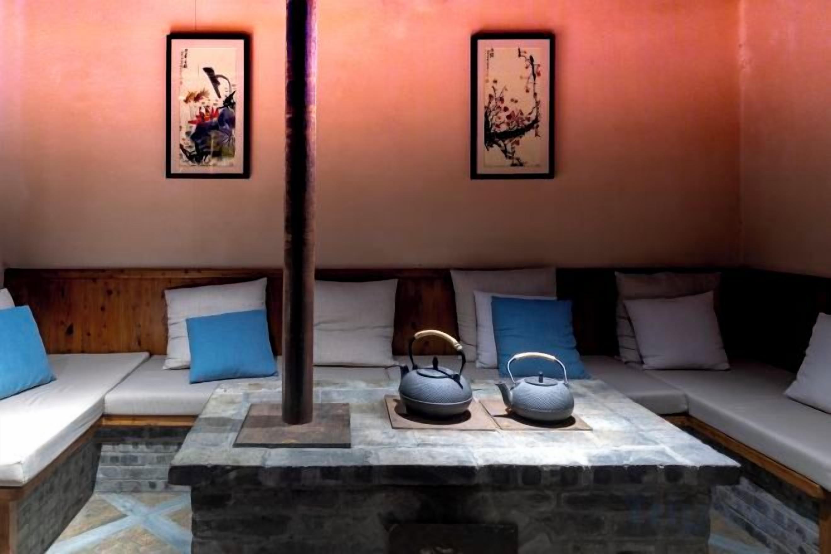 A room with a stone fireplace, a sofa with blue cushions, and two framed artworks on the wall.