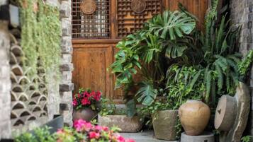 A traditional wooden door with a lattice design, surrounded by various potted plants and a stone wall.