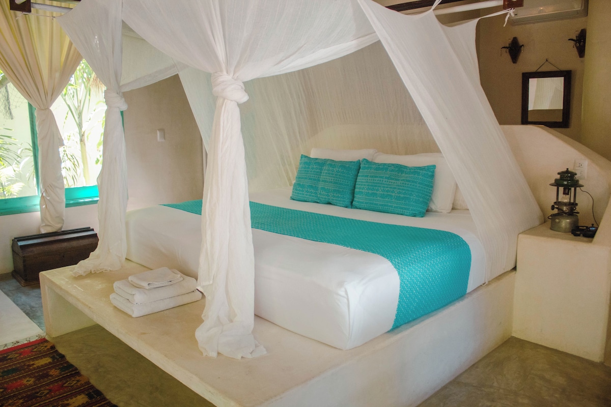 A bed with a canopy, a bedside table, and a small lamp.