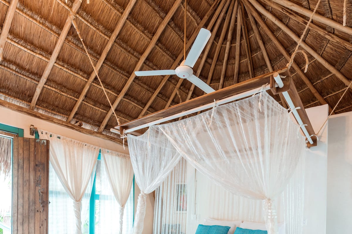 A spacious room with a large bed, a ceiling fan, and a canopy bed.