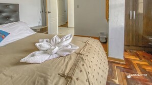 A bedroom with a bed, a bedside table, a wardrobe, and a bathroom visible through an open door. - Apartments Stunning View San Blas (Cusco)