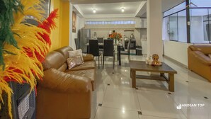A modern living room with a brown leather sofa, a wooden coffee table, and a dining area with a black table and chairs. - Apartments Stunning View San Blas (Cusco)