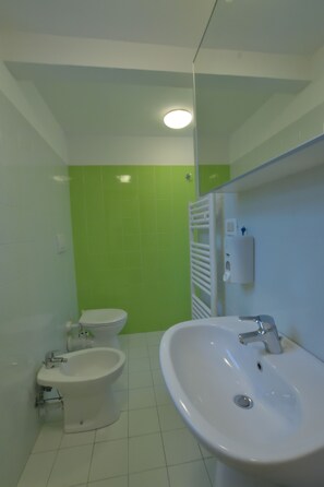 Un baño con inodoro, bidé y lavamanos.