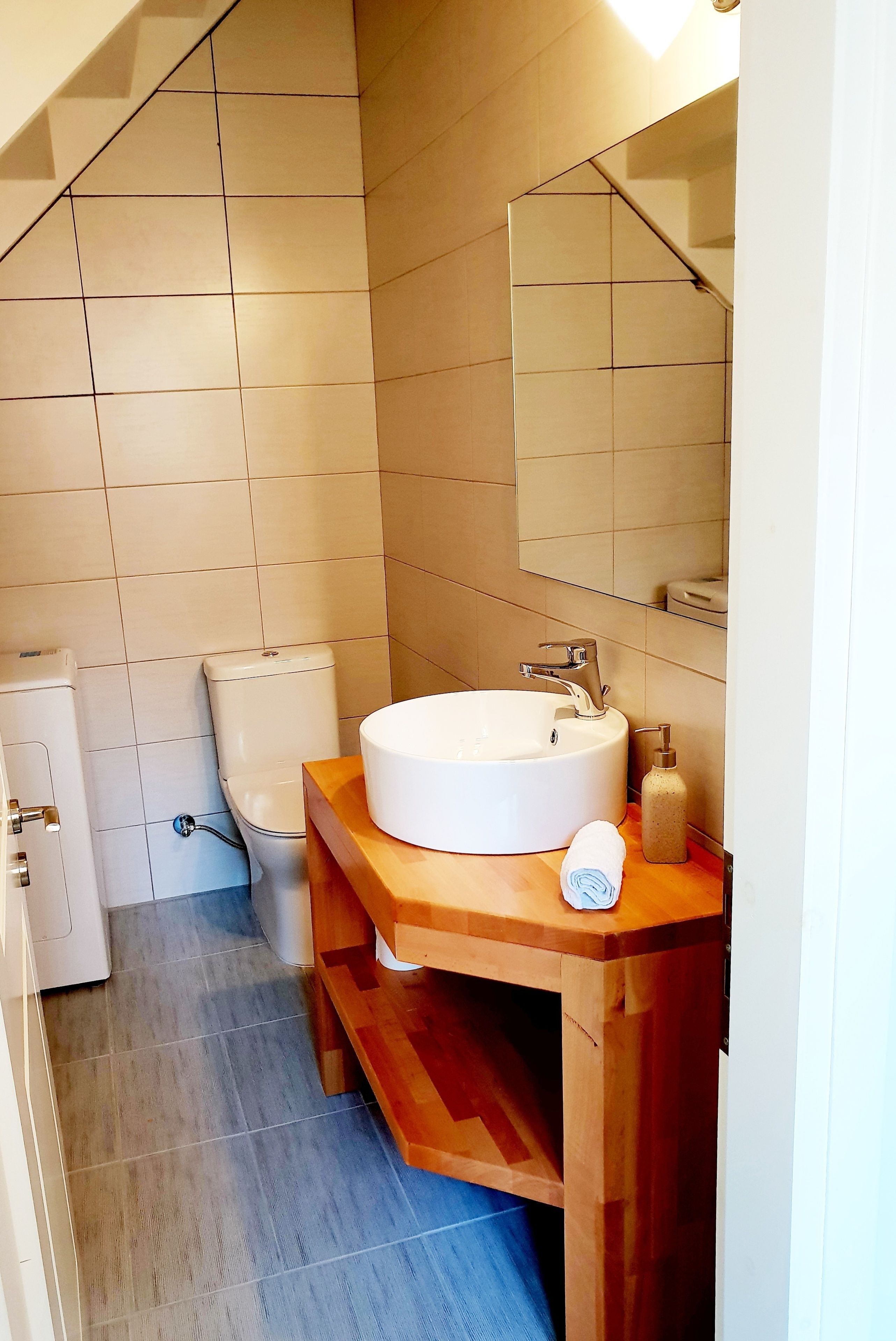 Ein Badezimmer mit einem weißen Waschbecken, einem Holz-Waschtisch und einem Spiegel darüber.