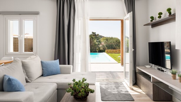 Un salon moderne avec un canapé, un téléviseur et une vue sur une piscine.