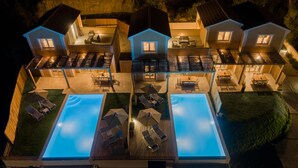 Un complexe hôtelier moderne doté de plusieurs villas, d’une piscine centrale et d’espaces de détente en plein air.