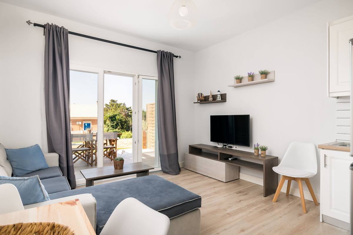 Een moderne woonkamer met een bank, een salontafel, een televisie en een eethoek met een tafel en stoelen.