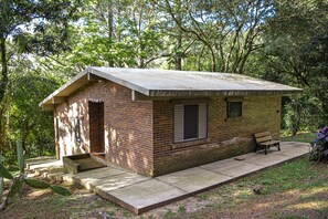 A small brick building with a concrete roof, a bench, and a set of stairs leading to an entrance. - Chalet em Viamão (Viamao)
