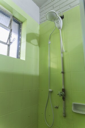 A bathroom with green tiles, a showerhead, and a window with a curtain. - Chalet em Viamão (Viamao)