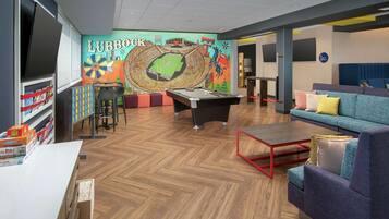 A lounge area with a pool table, seating, and a mural.