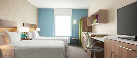 A hotel room with two beds, a desk with a computer, a TV, and a window with blinds.