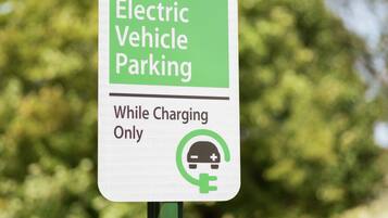 Señal que indica estacionamiento para vehículos eléctricos mientras se cargan.