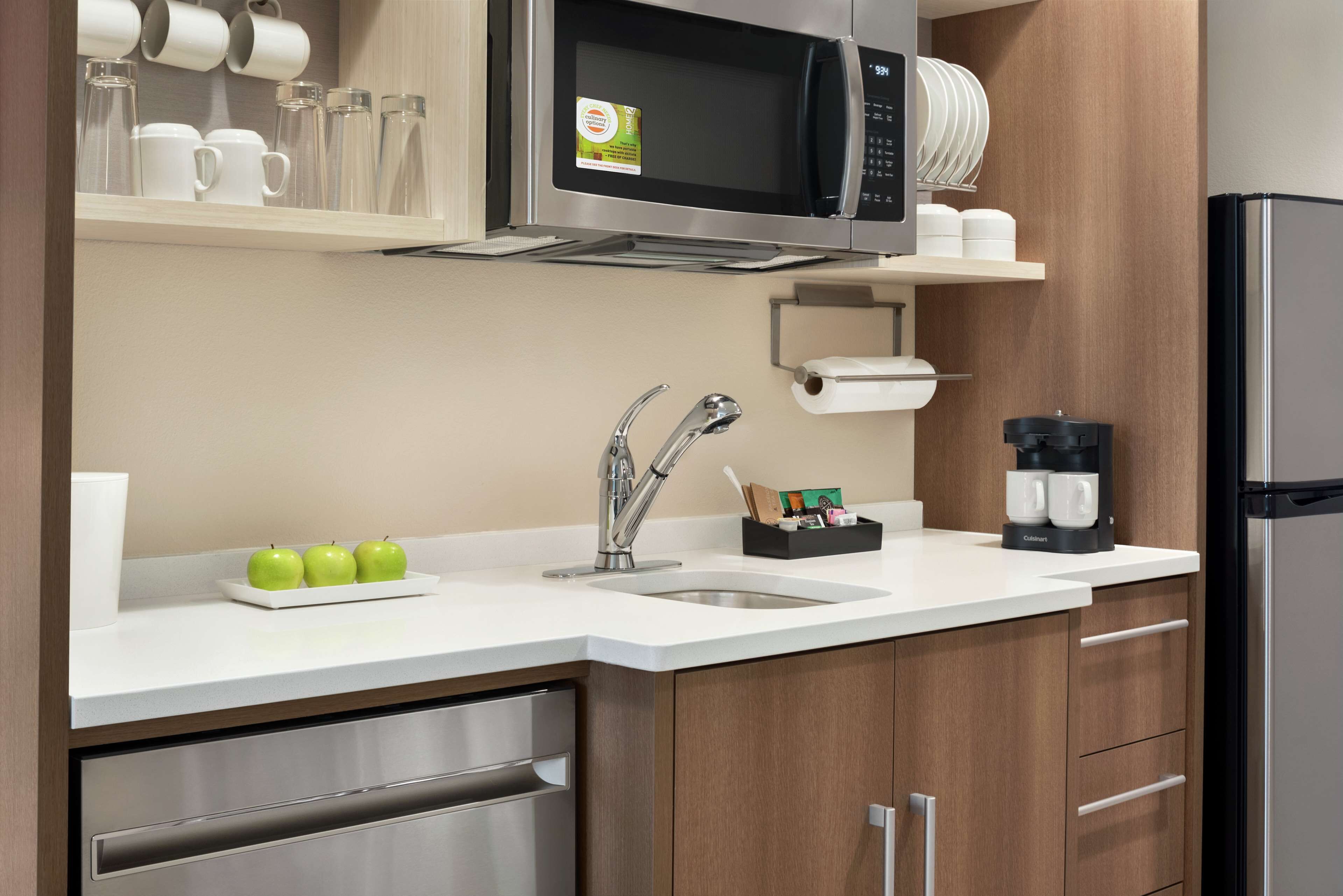 Una cocina moderna con un refrigerador de acero inoxidable, un microondas y un lavamanos.