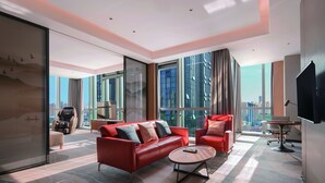 A modern hotel room with a red sofa, a small round table, and a city view through large windows. - DoubleTree by Hilton Suzhou Wujiang (Suzhou)