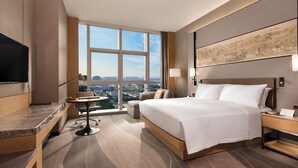 A modern hotel room with a large bed, a desk, a chair, a TV, and a view of the city. - DoubleTree by Hilton Suzhou Wujiang (Suzhou)