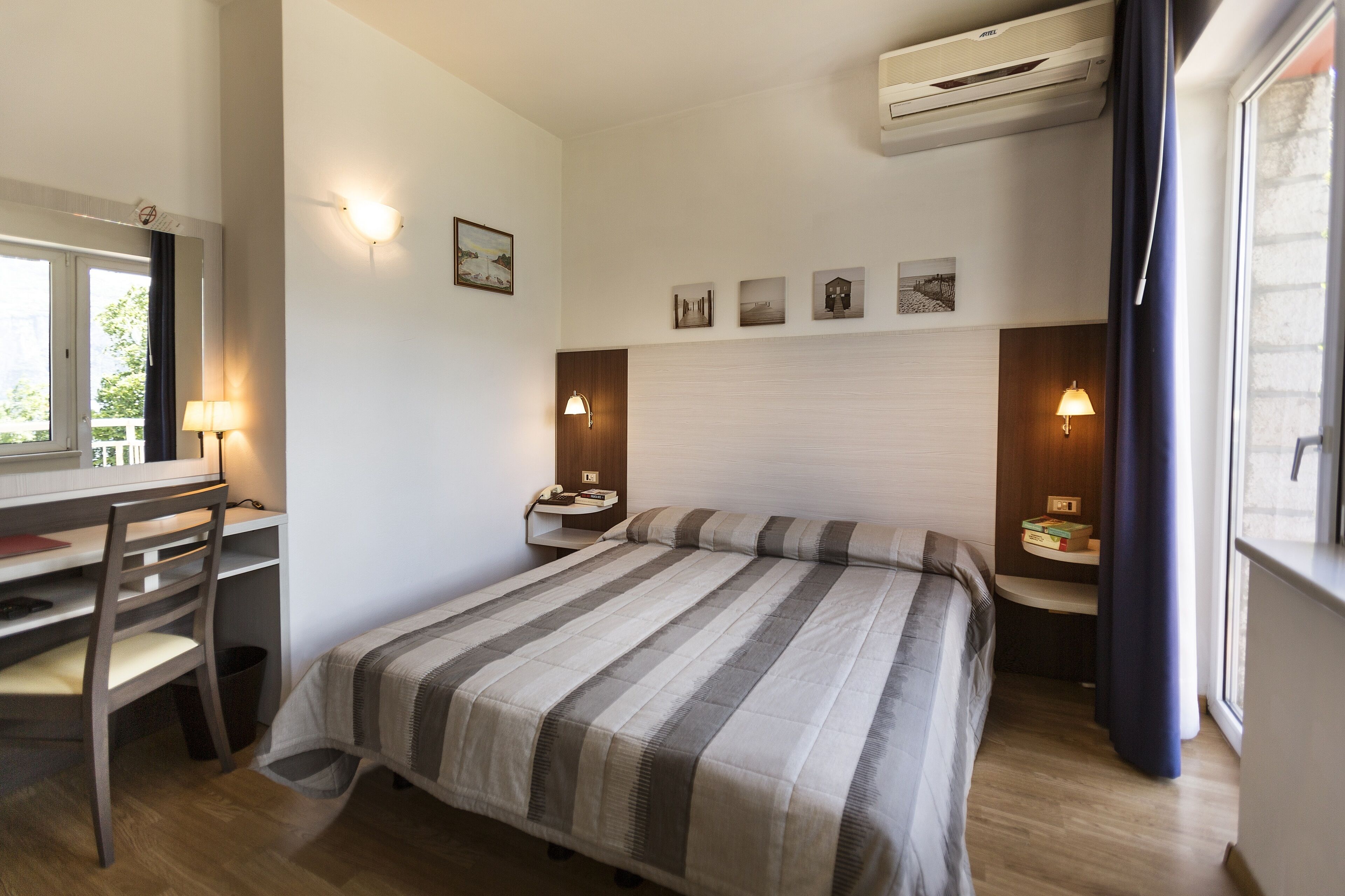 Ein Hotelzimmer mit Bett, Schreibtisch, Stuhl und Nachttischen.