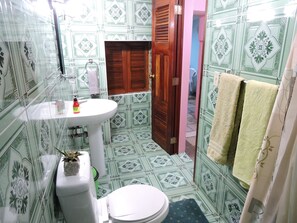 A compact bathroom with a traditional design, featuring a pedestal sink, toilet, and towel rack.