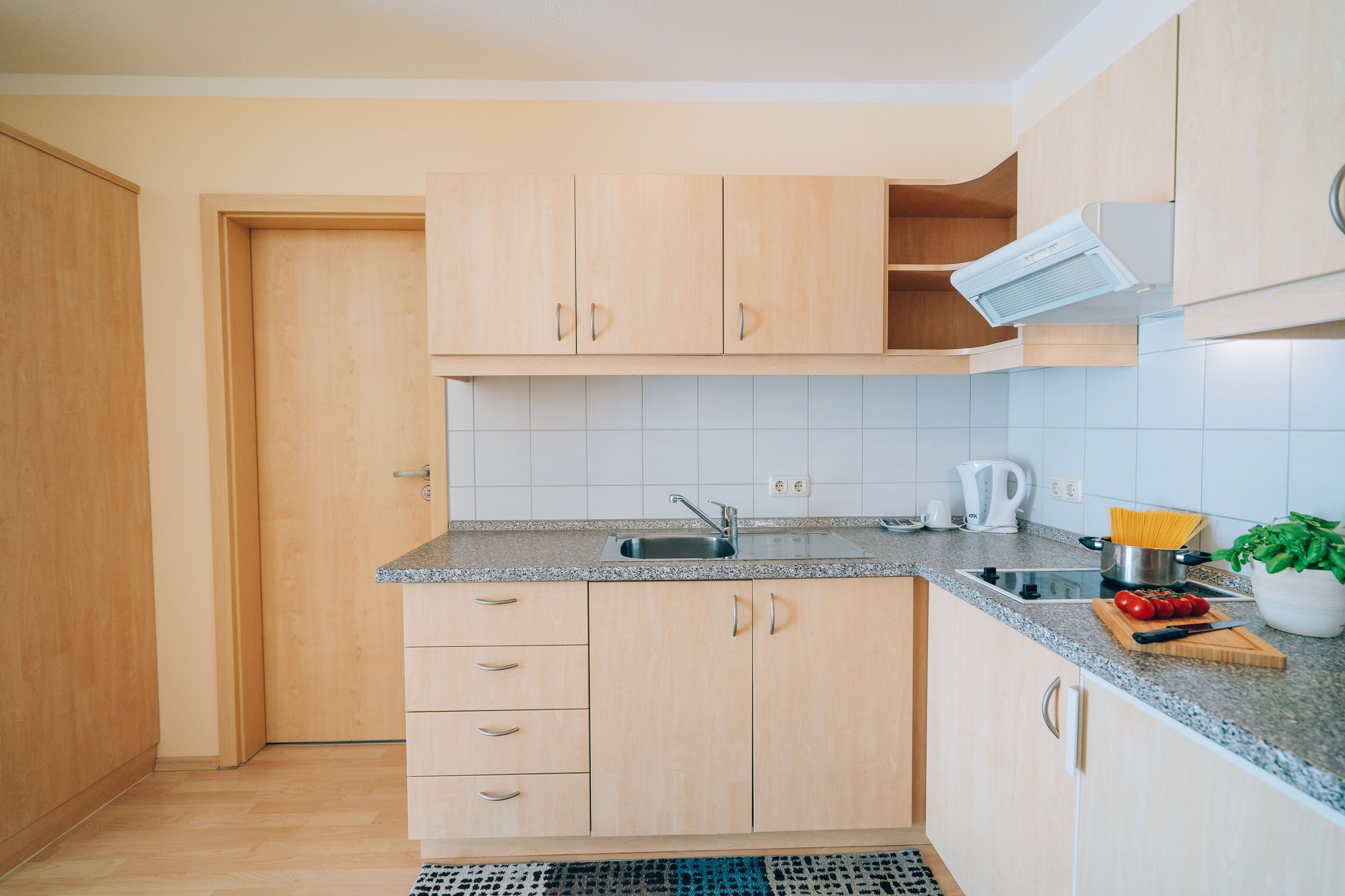 Una cocina con armarios de madera, encimera de granito, un lavamanos y una planta en maceta.