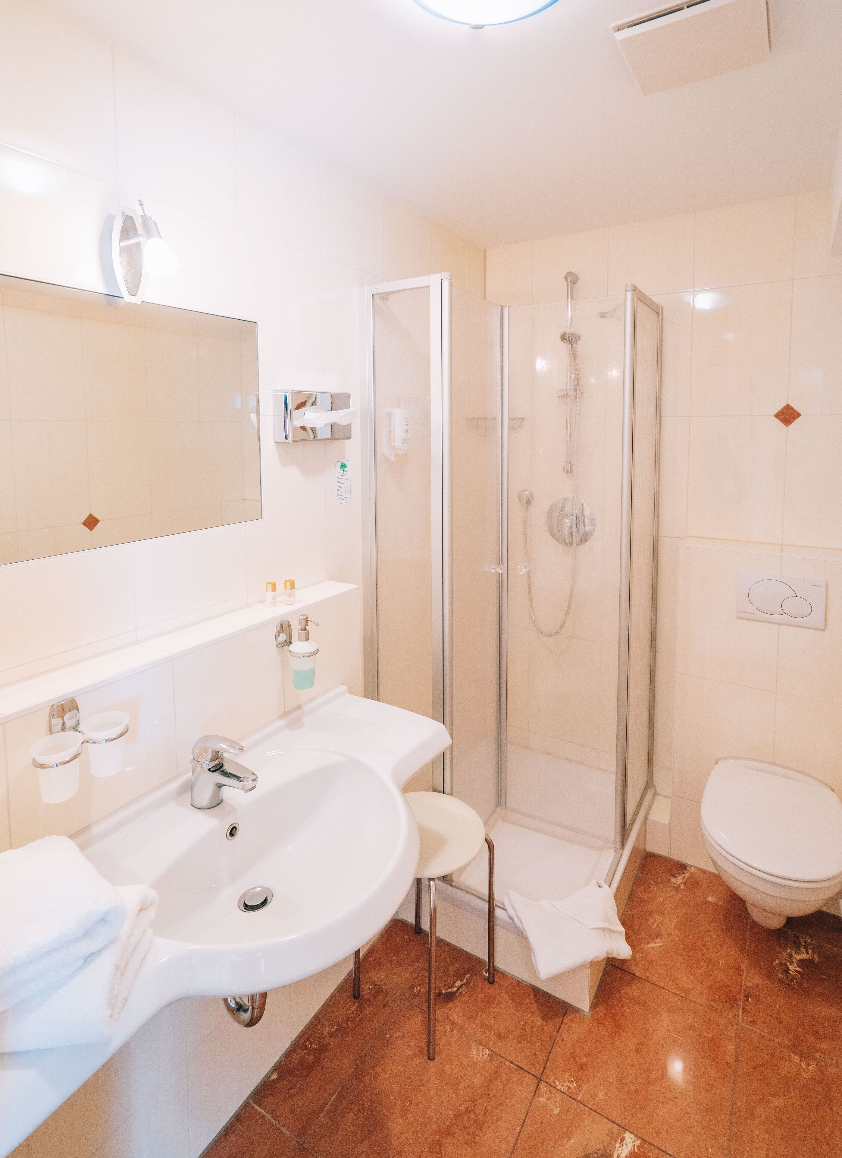 Un bany modern amb dutxa envidriada, un lavabo blanc i un vàter.