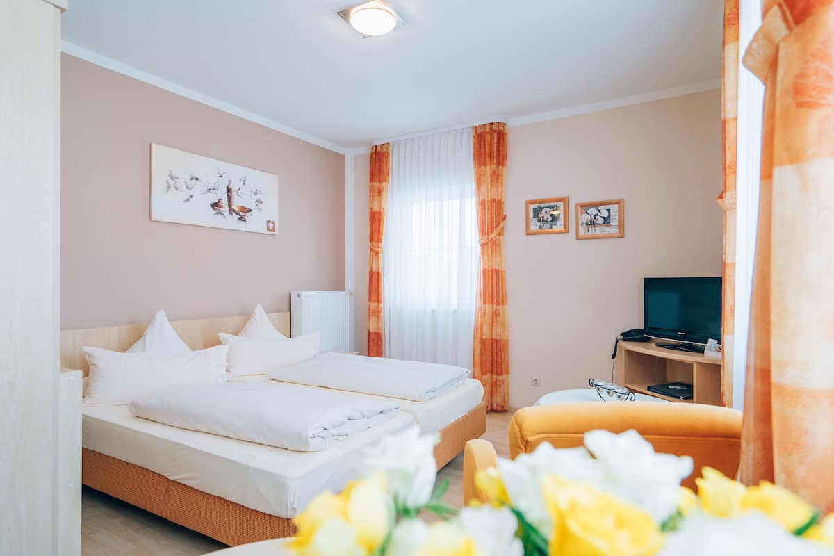 A hotel room with two beds, a television, and a small table.
