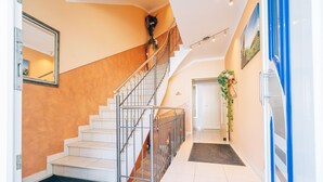 A modern interior with a staircase, a door, and a wall-mounted mirror. - Hotel Abenstal (Au in der Hallertau)