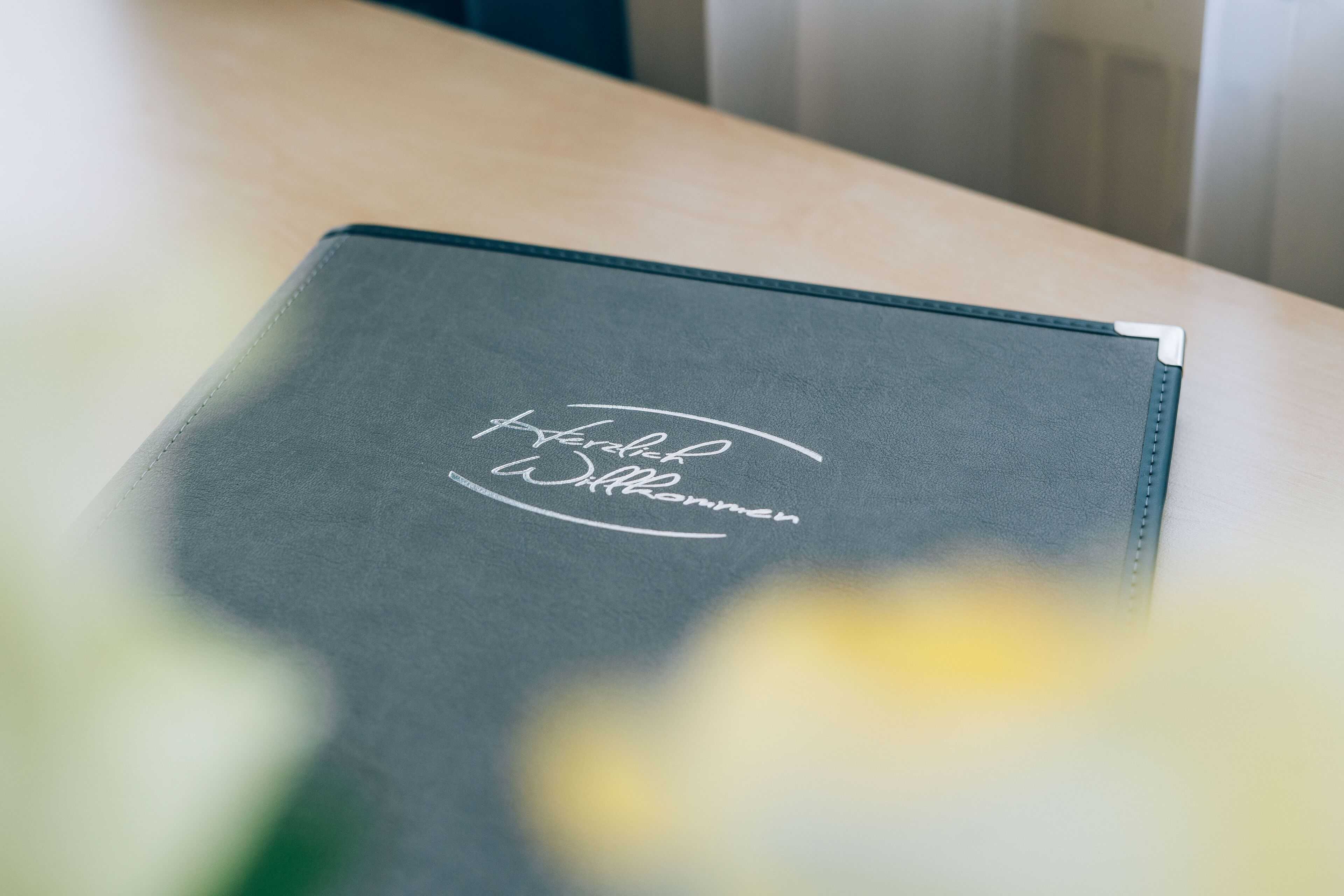 A black folder with the text "Hotel Wilhelmsen" on a wooden table.