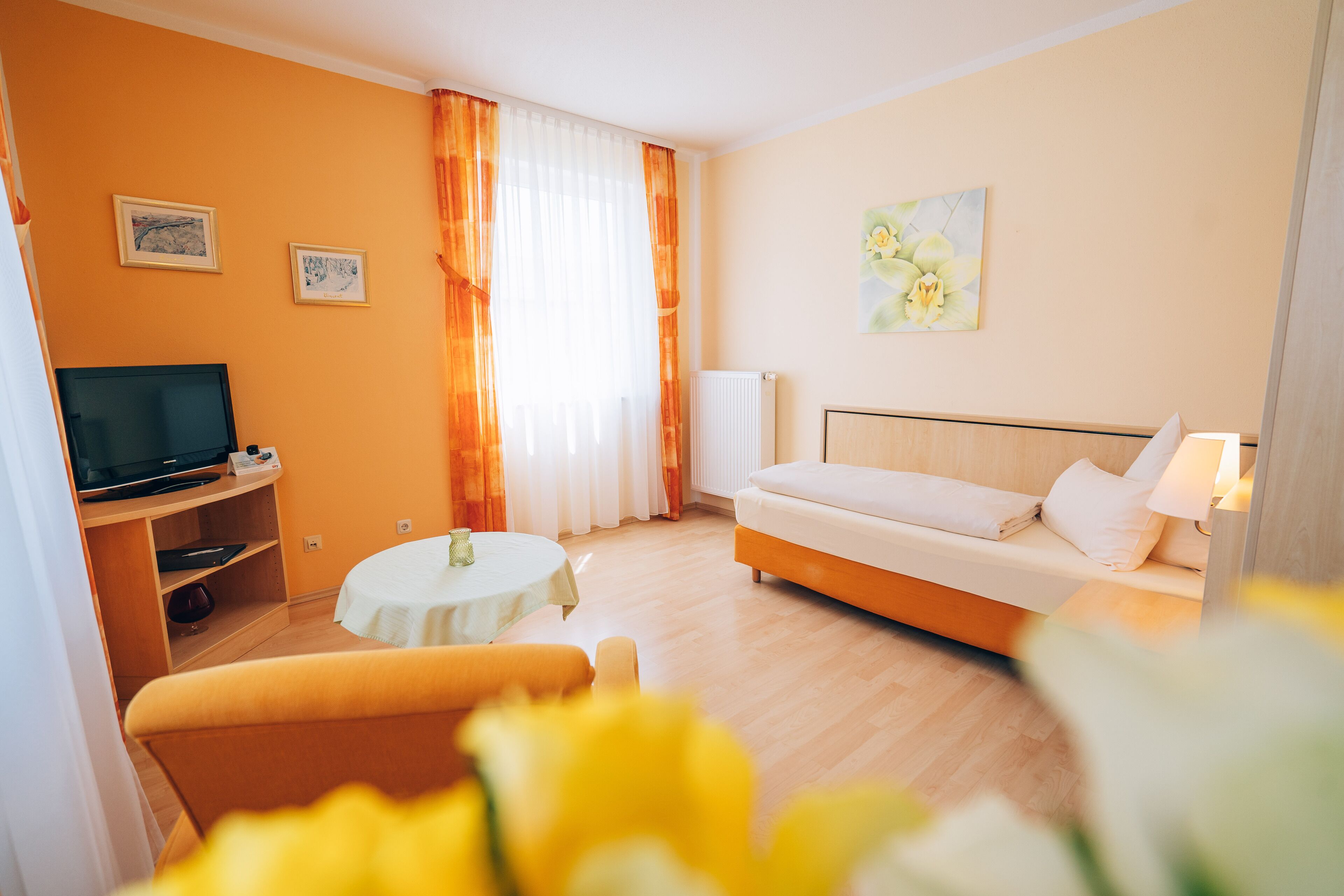 Una habitación de hotel con una cama, televisión, una mesita y un sofá.