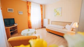 Una habitación de hotel con una cama, televisión, una mesita y un sofá.