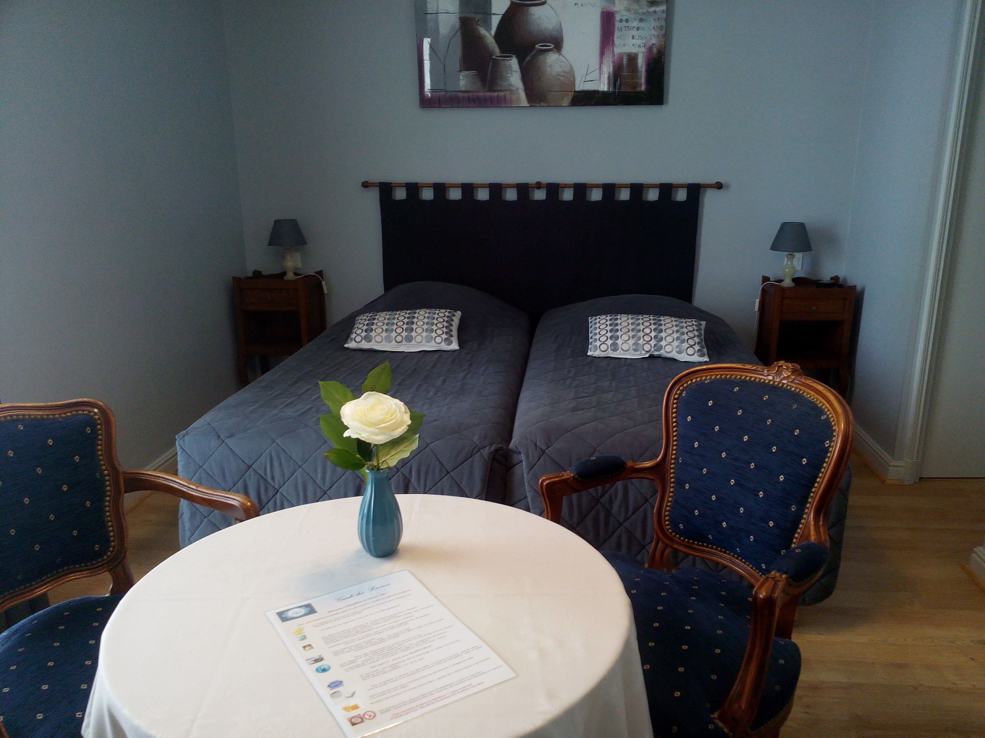 Ett hotellrum med två sängar, ett bord med en meny och en vas med en blomma.