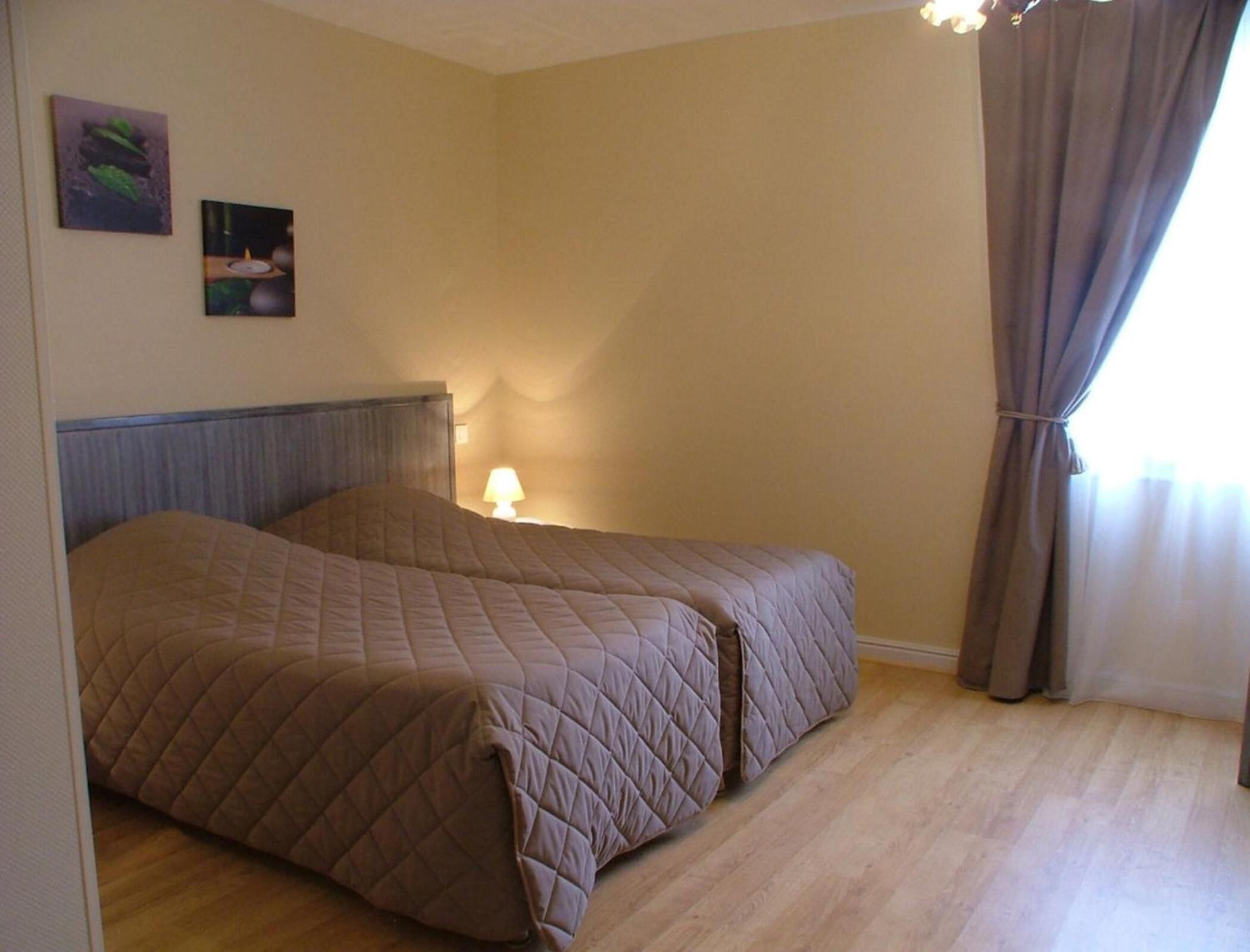 A bedroom with a bed, a nightstand, and two wall-mounted pictures.