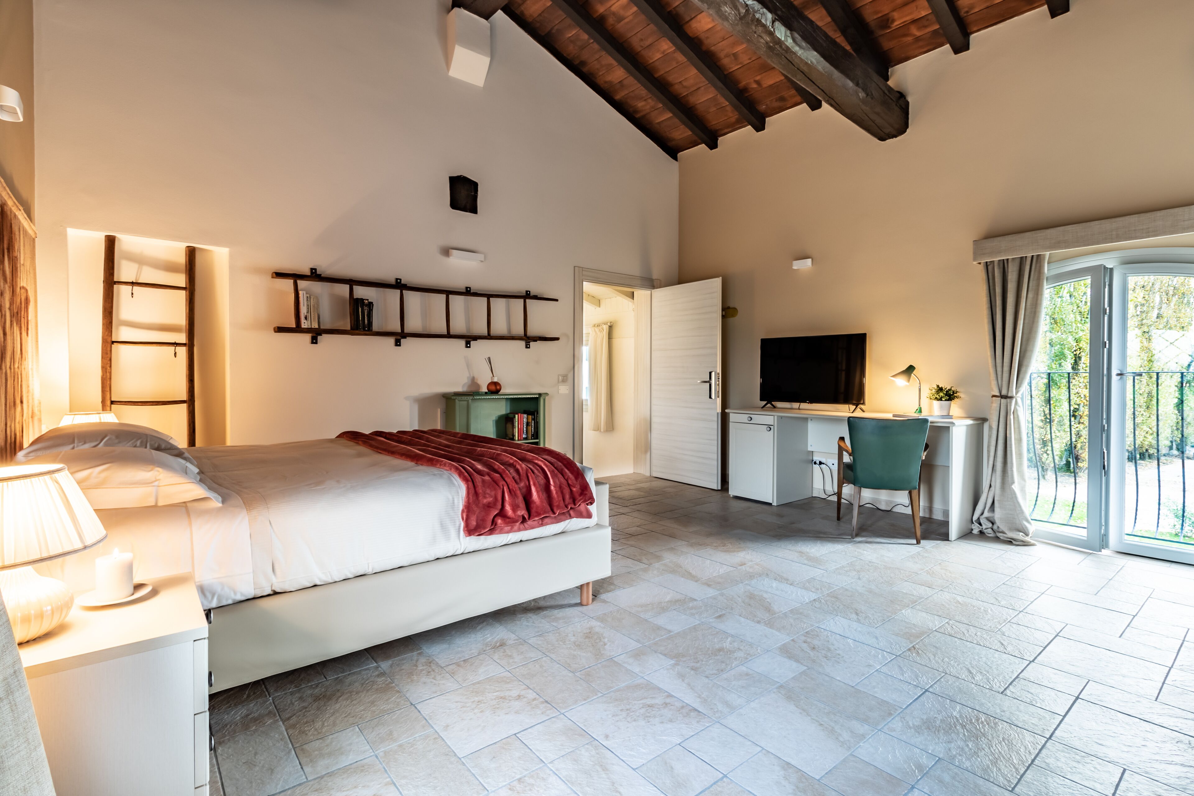Ein Schlafzimmer mit Bett, Nachttisch, Lampe und Schreibtisch mit Stuhl.